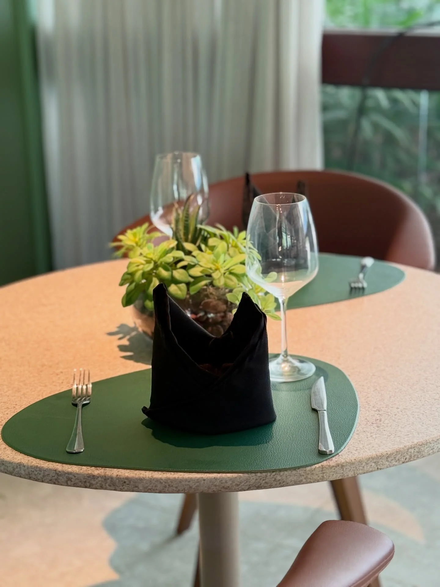 Detalhes da mesa posta no Spiaggia Verano, com taças, plantas e iluminação natural